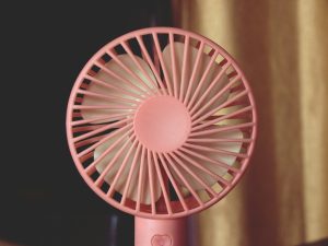 A pink fan sitting on top of a table